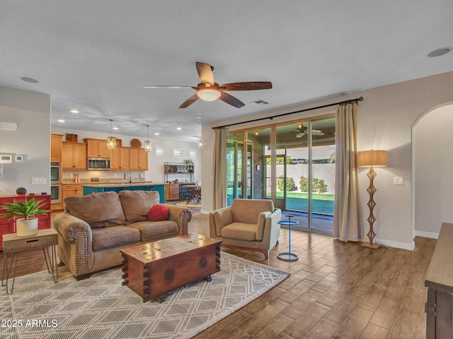 living room featuring ceiling fan, sink, and light hardwood / wood-style flooring