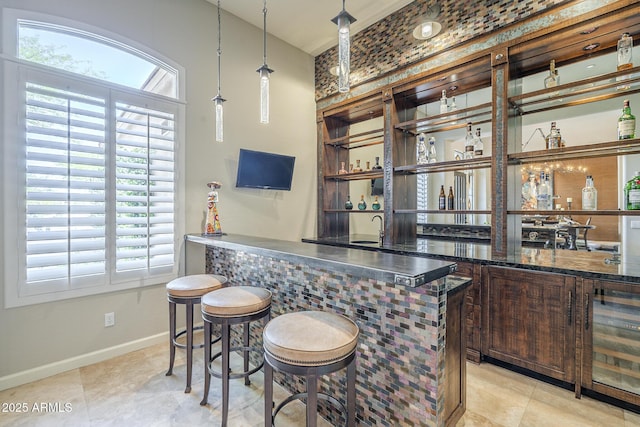 8248 E Arroyo Hondo Rd, Scottsdale, AZ 85266 - indoor wet bar featuring baseboards, healthy amount of natural light, beverage cooler, and hanging light fixtures