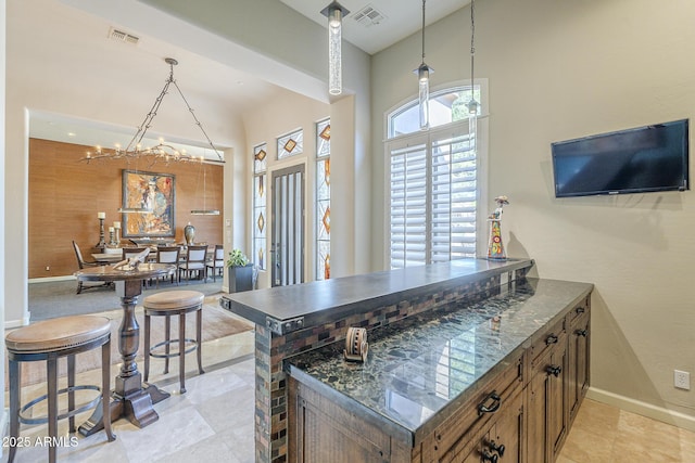 8248 E Arroyo Hondo Rd, Scottsdale, AZ 85266 - kitchen featuring baseboards, a peninsula, decorative light fixtures, brown cabinetry, and a high ceiling