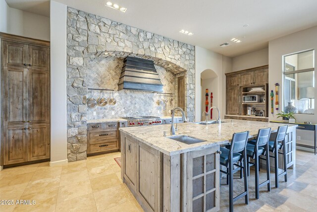 8248 E Arroyo Hondo Rd, Scottsdale, AZ 85266 - kitchen featuring a sink, custom range hood, light stone countertops, and arched walkways