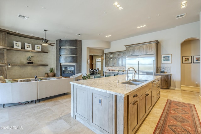8248 E Arroyo Hondo Rd, Scottsdale, AZ 85266 - kitchen featuring a sink, stainless steel built in refrigerator, a ceiling fan, light stone countertops, and an island with sink