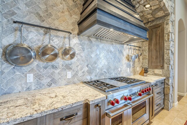 8248 E Arroyo Hondo Rd, Scottsdale, AZ 85266 - kitchen with custom range hood, double oven range, decorative backsplash, light stone counters, and baseboards