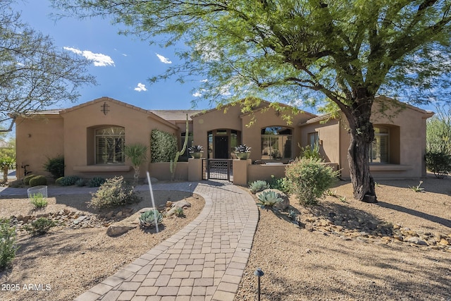 8248 E Arroyo Hondo Rd, Scottsdale, AZ 85266 - mediterranean / spanish home featuring a gate, stucco siding, and a fenced front yard