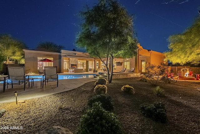 8248 E Arroyo Hondo Rd, Scottsdale, AZ 85266 - back of house at twilight with a patio, an outdoor pool, and stucco siding