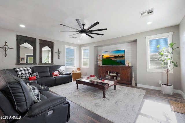 living room featuring visible vents, plenty of natural light, baseboards, and wood finished floors