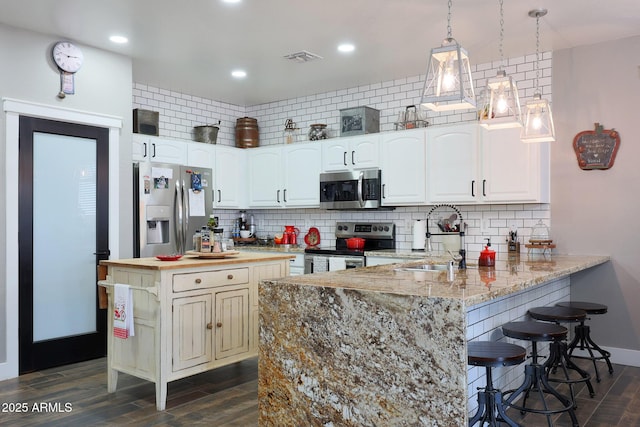 kitchen featuring stainless steel appliances, a sink, a peninsula, and decorative backsplash