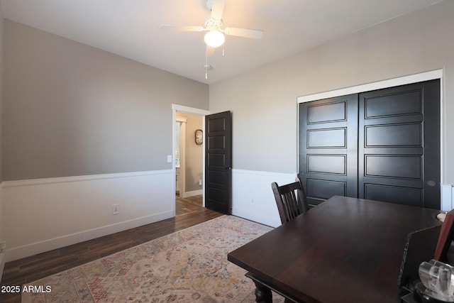 office featuring a wainscoted wall, wood finished floors, a ceiling fan, and baseboards