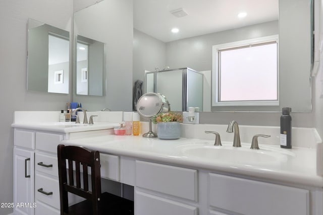 bathroom featuring double vanity, a stall shower, a sink, and recessed lighting