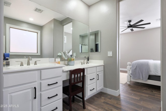 ensuite bathroom featuring visible vents, connected bathroom, vanity, wood finished floors, and baseboards