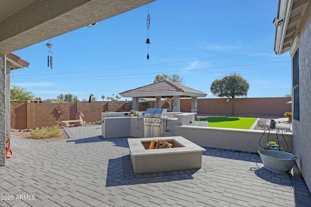 view of patio / terrace with an outdoor fire pit, a fenced backyard, grilling area, and an outdoor kitchen