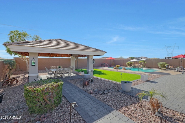 exterior space featuring a gazebo, outdoor dining area, a fenced backyard, and a fenced in pool