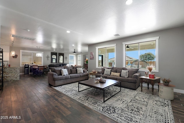 living room with ceiling fan, dark wood-style flooring, visible vents, and baseboards