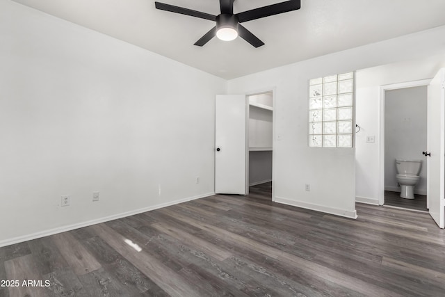 unfurnished bedroom featuring ensuite bath, a walk in closet, dark hardwood / wood-style flooring, a closet, and ceiling fan