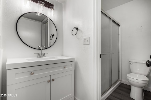 bathroom featuring an enclosed shower, vanity, wood-type flooring, and toilet