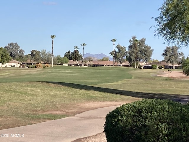 view of community with a lawn, view of golf course, and a mountain view