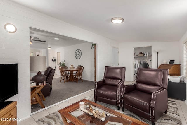 tiled living room featuring ceiling fan and washing machine and clothes dryer