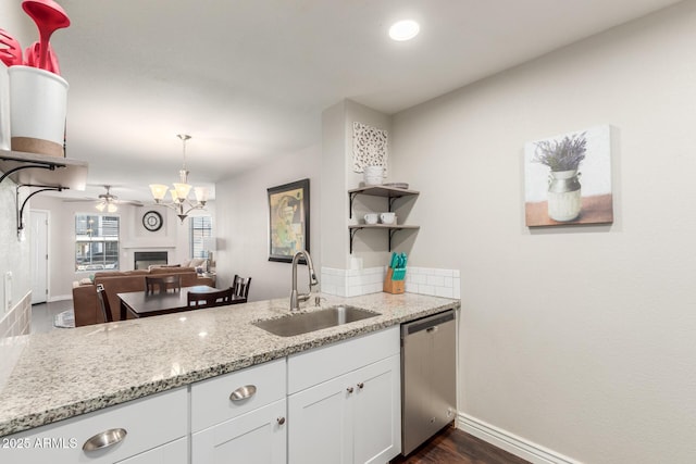 kitchen featuring dishwasher, a fireplace, white cabinetry, open shelves, and a sink