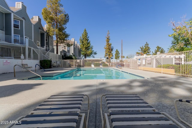 community pool featuring a residential view, fence, and a patio