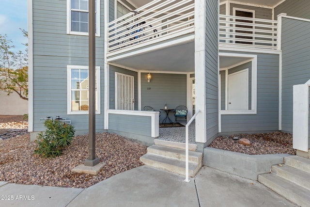 view of exterior entry with a porch and a balcony