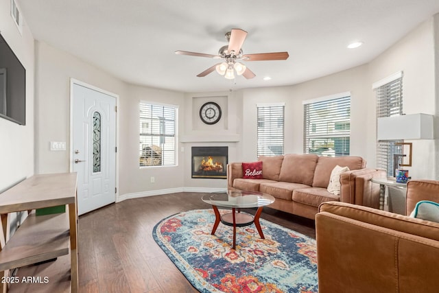 living room featuring a glass covered fireplace, wood-type flooring, visible vents, and plenty of natural light