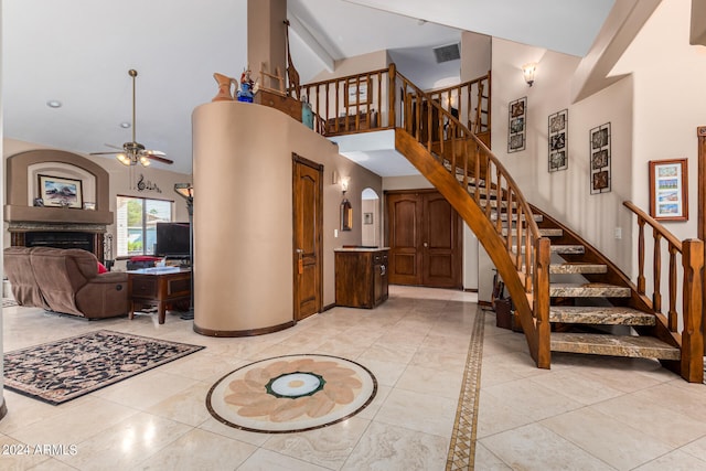 stairs with tile patterned floors, high vaulted ceiling, and ceiling fan