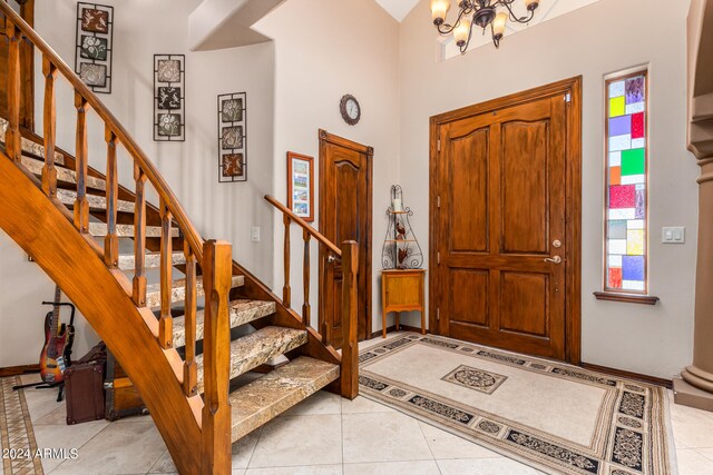 tiled entrance foyer featuring an inviting chandelier and a high ceiling