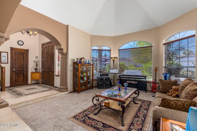 carpeted living room with ornate columns and high vaulted ceiling