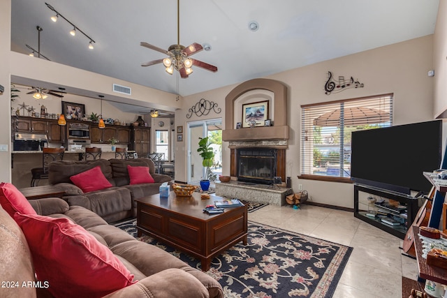 living room with ceiling fan, a fireplace, light tile patterned floors, and plenty of natural light