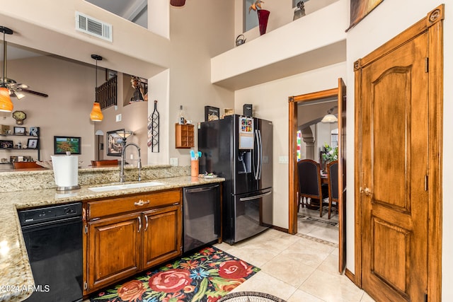 kitchen with stainless steel dishwasher, black fridge with ice dispenser, sink, pendant lighting, and light stone counters