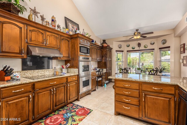 kitchen with appliances with stainless steel finishes, ceiling fan, vaulted ceiling, light stone counters, and light tile patterned floors