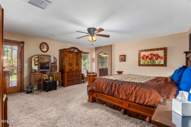 bedroom with ensuite bath, light carpet, multiple windows, and ceiling fan