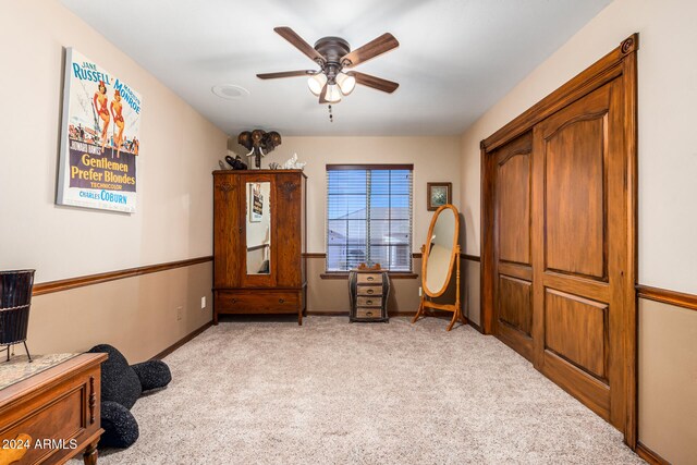 living area with light carpet and ceiling fan