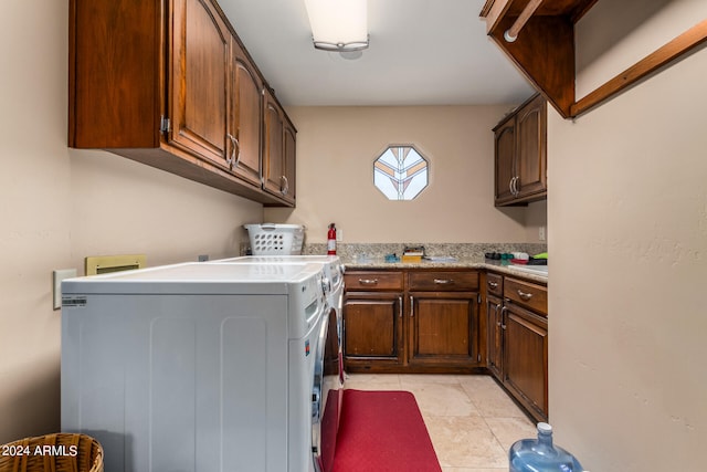 clothes washing area featuring light tile patterned floors, cabinets, and washer and clothes dryer