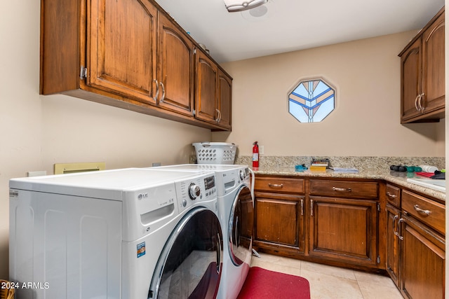 clothes washing area with washer and clothes dryer, light tile patterned floors, and cabinets