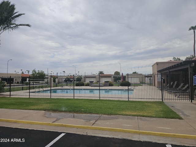 community pool featuring fence and a lawn