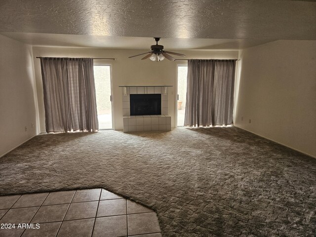 unfurnished living room featuring a healthy amount of sunlight, a fireplace, light carpet, and a textured ceiling