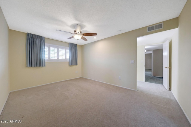 spare room with light carpet, a textured ceiling, baseboards, visible vents, and ceiling fan