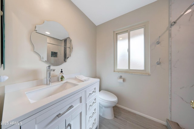 bathroom featuring toilet, vanity, a marble finish shower, wood finished floors, and baseboards