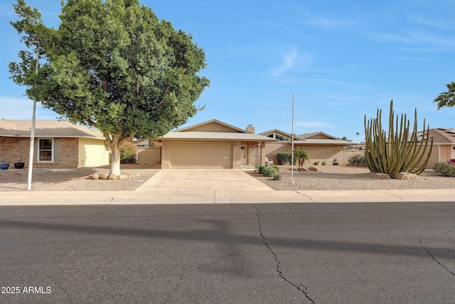 view of front facade featuring fence, driveway, a garage, and brick siding