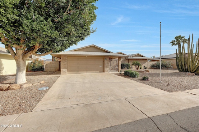 single story home featuring brick siding, concrete driveway, fence, and an attached garage