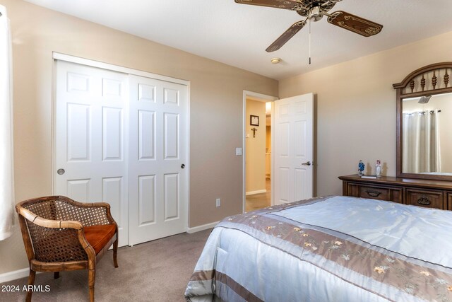 bedroom with ceiling fan, light colored carpet, and a closet