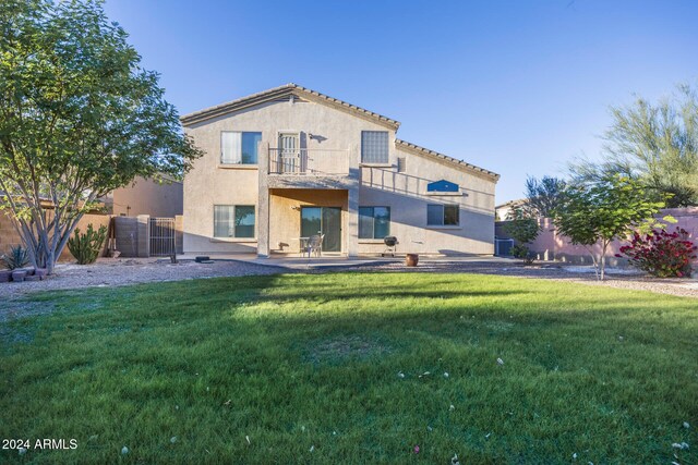 rear view of house with a balcony and a lawn