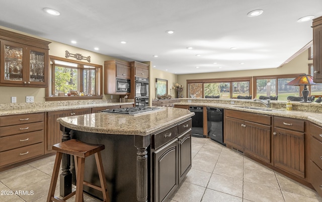 kitchen with a sink, a center island, black appliances, and a healthy amount of sunlight