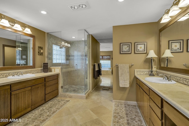 full bath featuring two vanities, a healthy amount of sunlight, and a sink