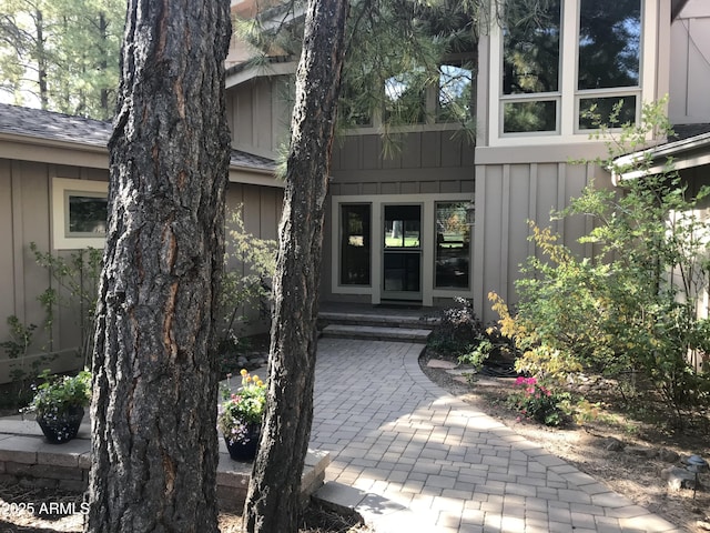 doorway to property with roof with shingles and board and batten siding