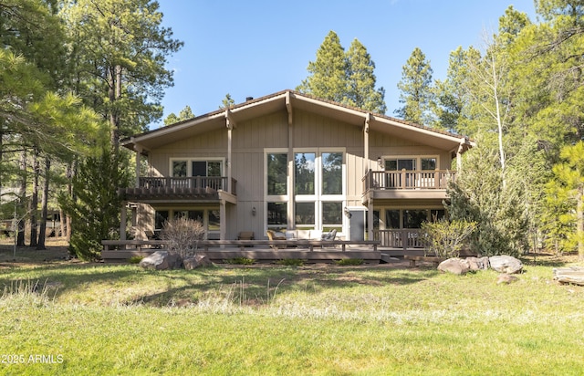 back of property with a yard, a wooden deck, and a balcony