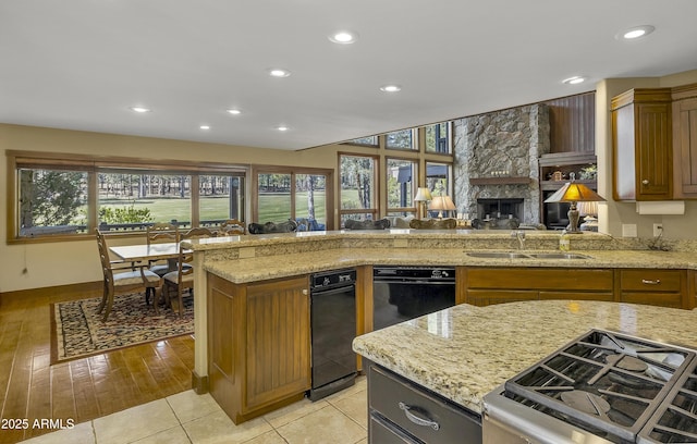 kitchen featuring plenty of natural light, brown cabinetry, light stone countertops, a sink, and recessed lighting