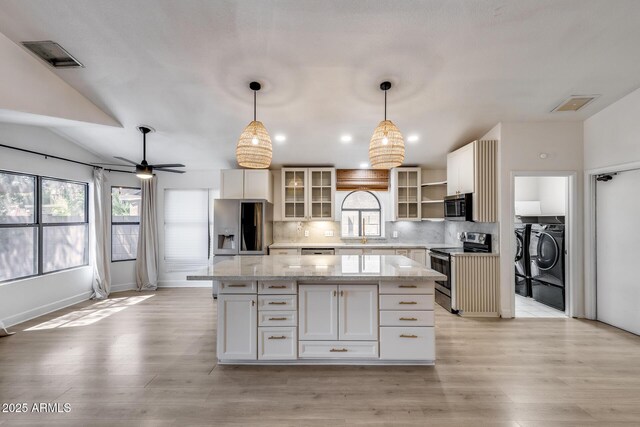4443 W Escuda Dr, Glendale, AZ 85308 - kitchen with appliances with stainless steel finishes, washing machine and clothes dryer, a center island, light wood-style flooring, and tasteful backsplash