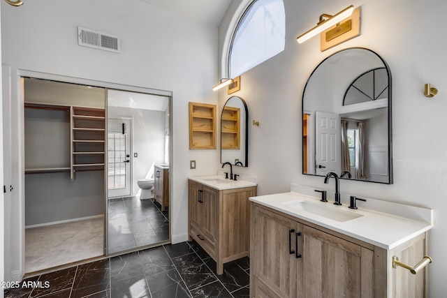 4443 W Escuda Dr, Glendale, AZ 85308 - bathroom featuring marble finish flooring, healthy amount of natural light, two vanities, a high ceiling, and baseboards