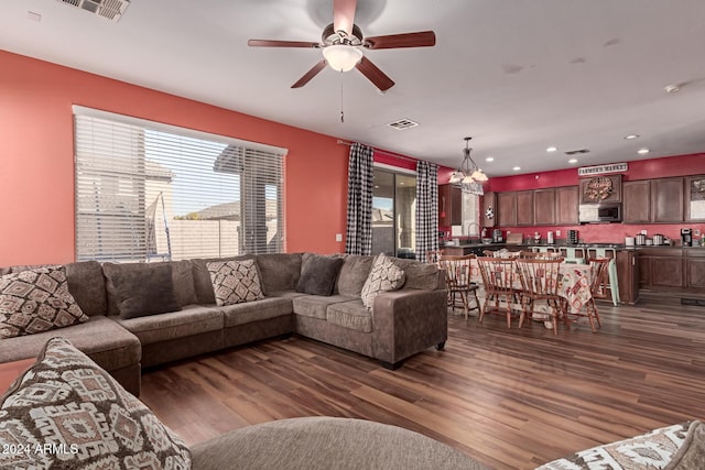 living room with ceiling fan with notable chandelier, dark hardwood / wood-style floors, and sink